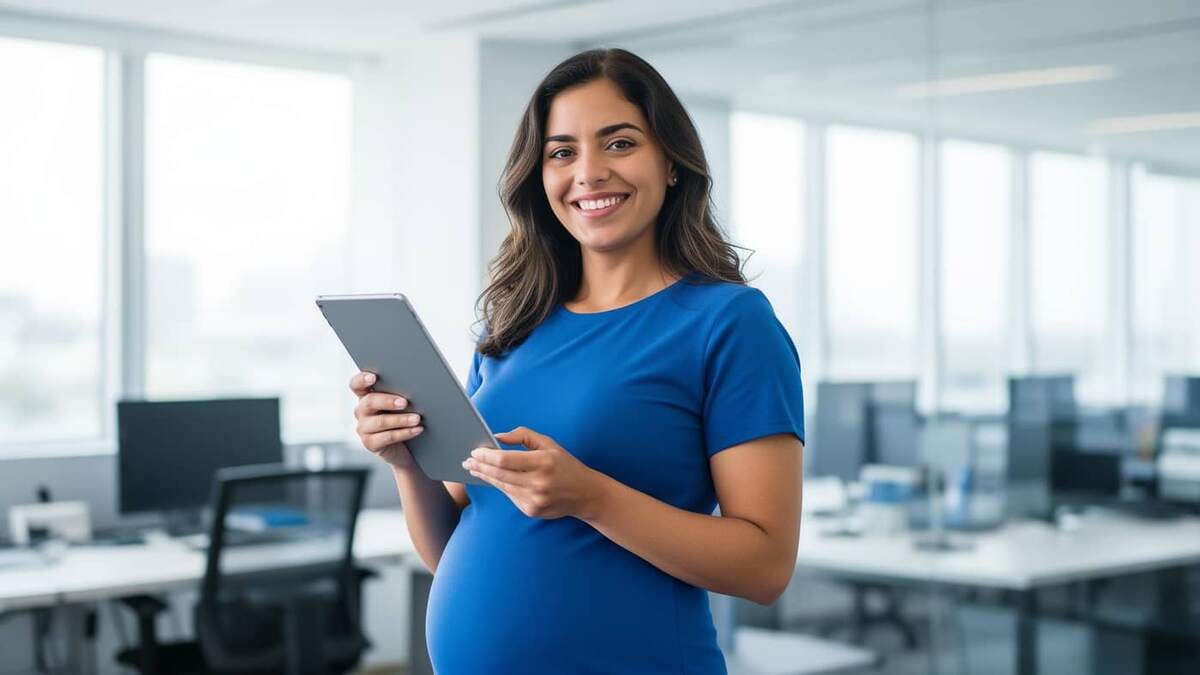 Gestante sorridente em escritório moderno e iluminado segurando um tablet, representando o planejamento da licença maternidade